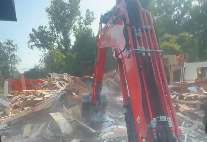 Excavator boom over a pile of demolition debris, seen from the cab, near Hammond, LA