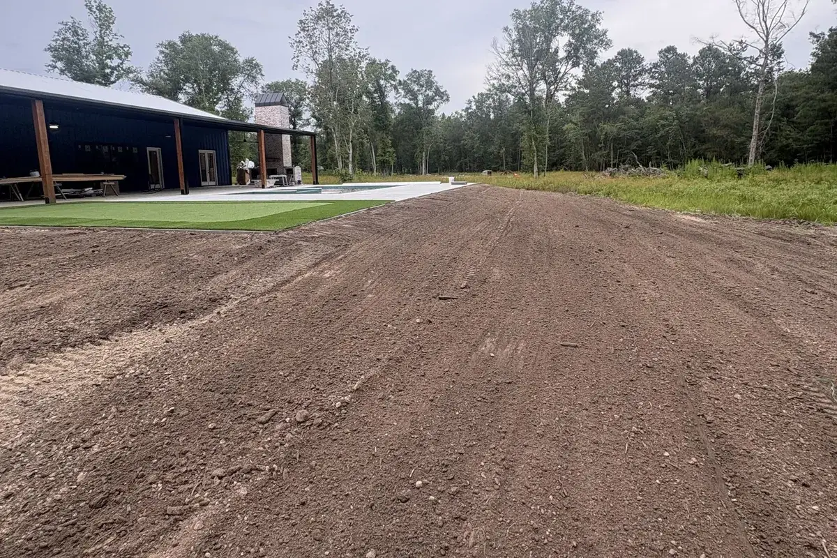 Graded road bed running past a metal building toward the tree line near Hammond, LA